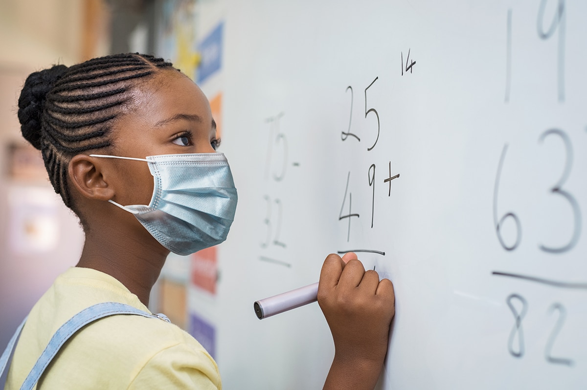 photo: Young girl doing math problems at school during pandemic